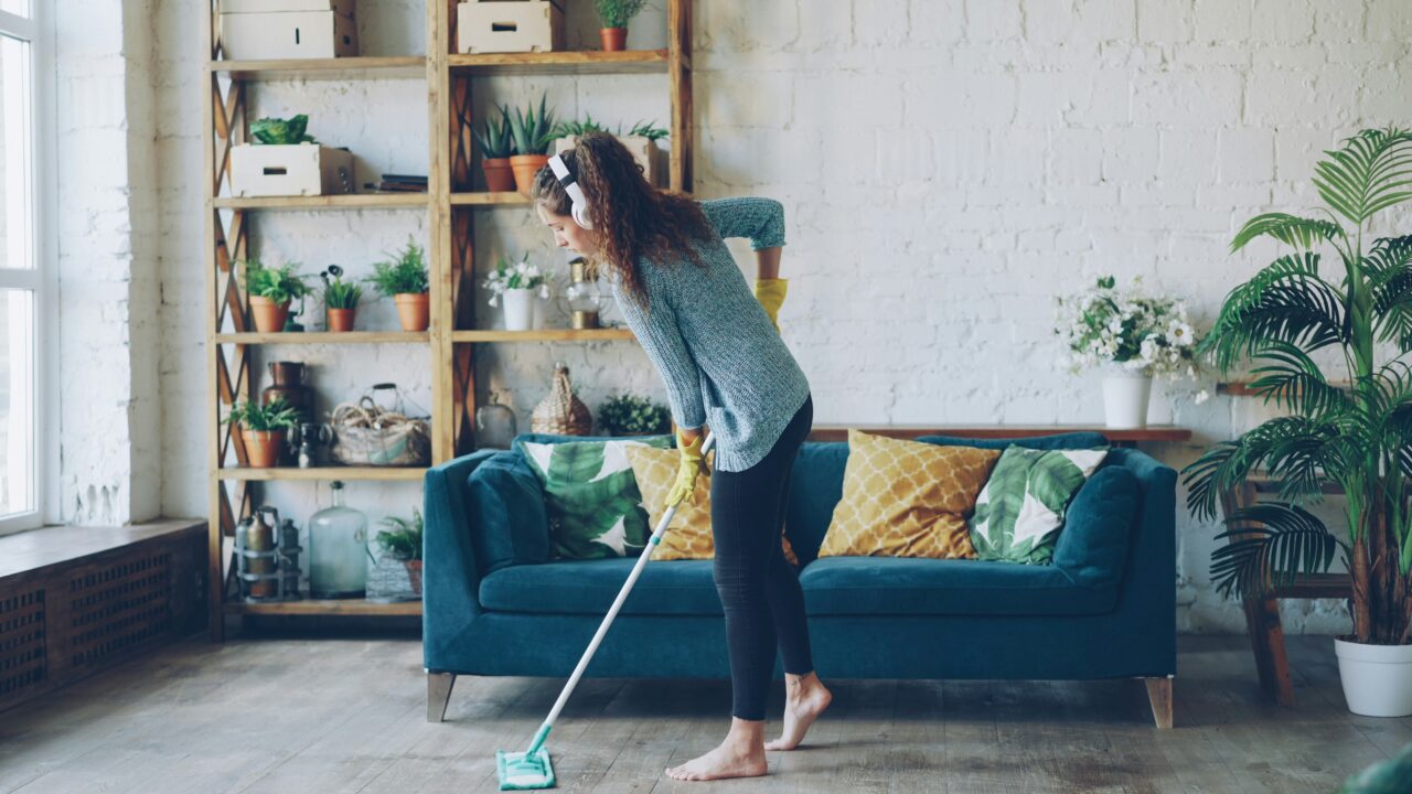 Woman mopping floor while wearing headphones.