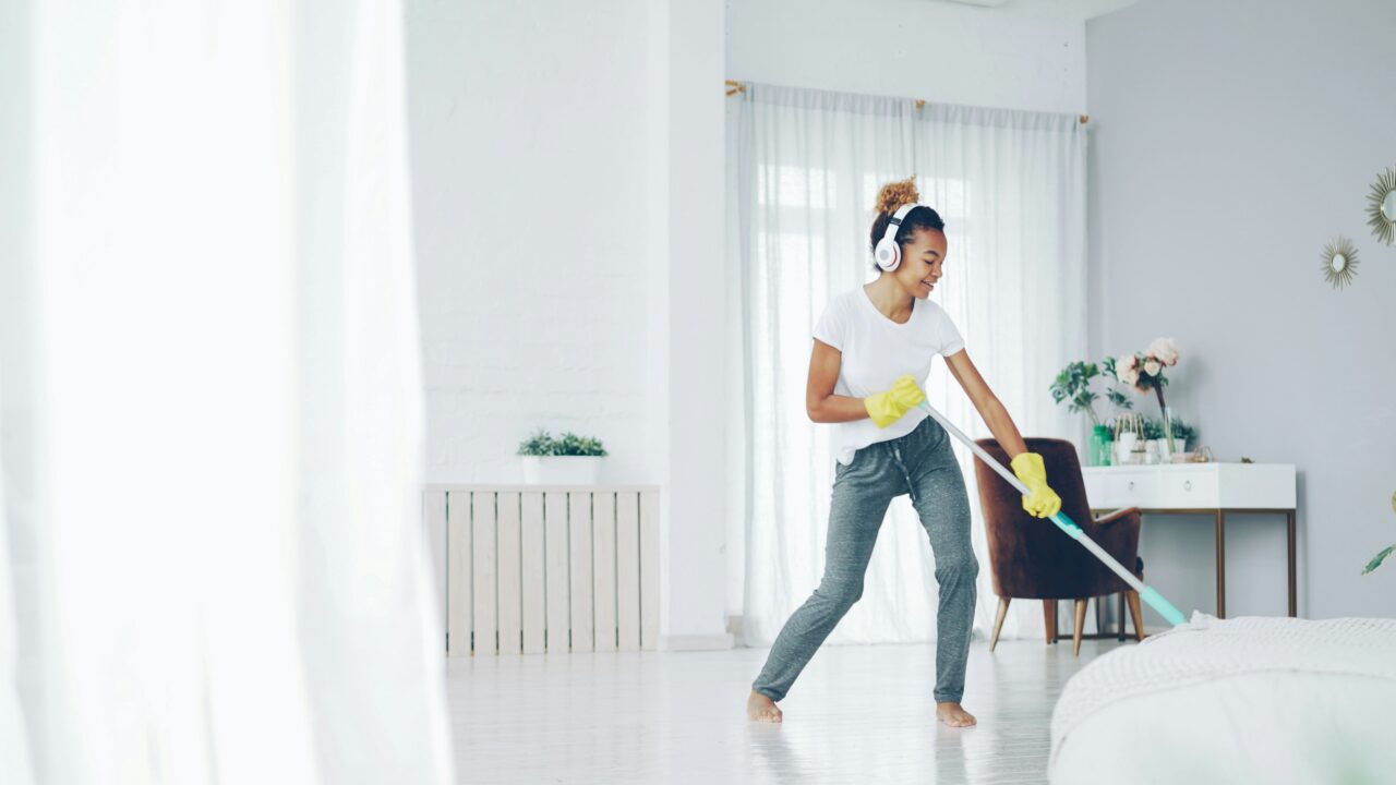 Woman with headphones cleaning and dancing happily